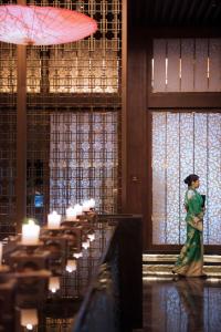 a woman walking through a room with tables and candles at Wanda Reign Wuhan in Wuhan +48 photos