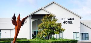 een links parkhotelgebouw met een standbeeld ervoor bij JetPark Hamilton Airport New Zealand in Hamilton