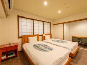 1 dormitorio con 2 camas y mesa en Miro Hotel Dotonbori, en Osaka