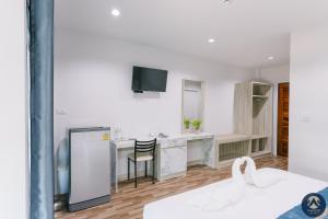 a white room with a kitchen with a table and a chair at Thepchamrat Boutique Hotel in Uttaradit