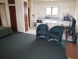 a room with two chairs and a kitchen at castletown motel in Foxton