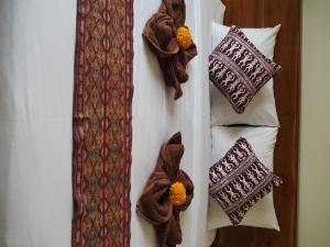 un grupo de almohadas y una corbata en una cama en Kampung Sari Homestay en Ubud