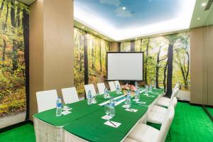una sala de conferencias con una mesa larga con sillas y una pantalla en Royal City Hotel, en Yakarta