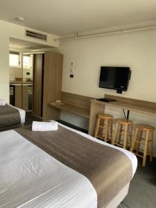 a hotel room with two beds and a flat screen tv at Huskisson Beach Motel in Huskisson