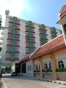 a large white building with green balconies on it at Nan Chao Hotel in Phitsanulok