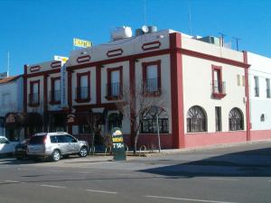 un bâtiment rouge et blanc au coin d'une rue dans l'établissement Hostal Restaurante Milenium, à Torremegía