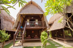 Cette maison dispose d'un toit de chaume et d'un balcon. dans l'établissement Nanuk's Bungalows, à Nusa Lembongan