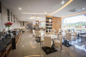 Lintas Platinum Hotel في كوتا كينابالو: مطعم بطاولات بيضاء وكراسي ونافذة كبيرة