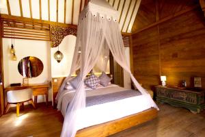 a large bed with a canopy on top of it at Natya Hotel Tanah Lot in Tanah Lot
