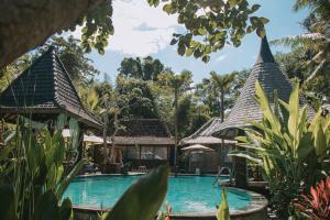 克拉玛斯Keramas Sacred River Retreat Resort and Villa的一座位于树荫下的度假村的游泳池