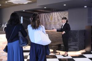 un hombre está dando una presentación a dos mujeres en The Celecton Tsuchiura Ekimae, en Tsuchiura