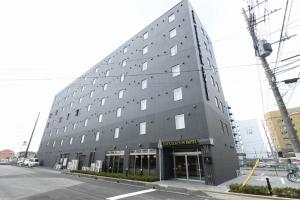 un grand bâtiment gris avec des fenêtres donnant sur une rue dans l'établissement The Celecton Tsuchiura Ekimae, à Tsuchiura