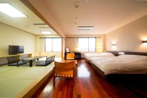 um quarto de hotel com duas camas e uma mesa em Kikunan Onsen Yubel Hotel em Kumamoto