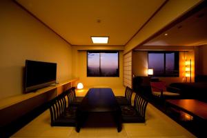 Habitación con mesa, sillas y TV. en Kikunan Onsen Yubel Hotel, en Kumamoto