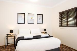 a bedroom with a white bed with three pictures on the wall at Mason Winery in Mount Tamborine
