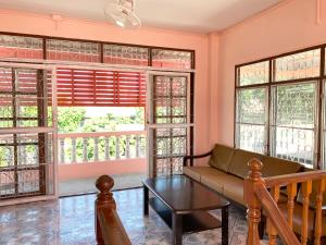 a living room with a couch and a table and windows at Gaiwandhanat Homestay in Bangkok