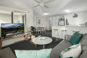 uma sala de estar com um sofá, uma televisão e uma cozinha em Riverside location, Noosa Sound em Noosa Heads