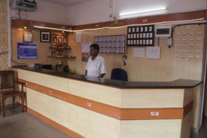 a man standing behind the counter of a restaurant at Santosh Lodge in Dod Ballāpur