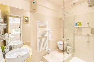 La salle de bains blanche est pourvue d'une douche et de toilettes. dans l'établissement Acropolis Suites - Where else in Athens?, à Athènes