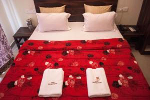 un letto con una coperta rossa e due asciugamani sopra di Hotel Govindpuram a Kolhapur