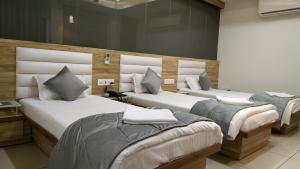 KalolHOTEL SATKAR CHHATRAL的一间房间里有三张床的卧室
