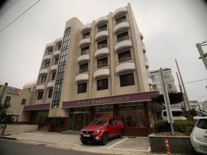済州市にあるJeju Renaissance Hotelの建物前に停車する赤い車