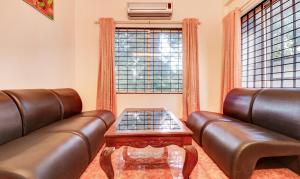 uma sala de estar com dois sofás de couro e uma mesa em Itsy By Treebo - Ammu Regency em Thrissur