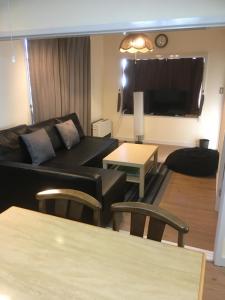 a living room with a black couch and a table at Kotori Cottage in Hakuba