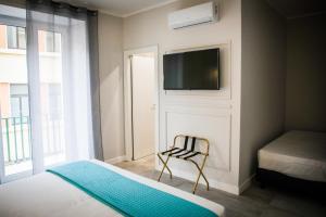 een slaapkamer met een bed, een tv en een stoel bij Principessa Isabella Luxury Rooms in Salerno