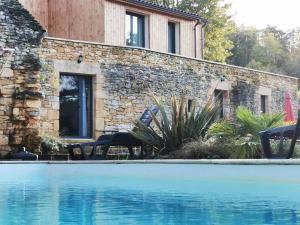 une maison avec une piscine en face d'un bâtiment dans l'établissement Gîte Les Combes Montignac Lascaux, à Montignac