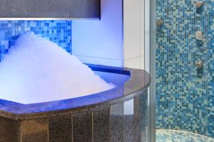 a bath tub with a blue and white shower curtain at Steigenberger Airport Hotel Amsterdam in Schiphol