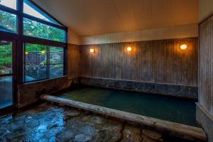a bath tub in a room with a pool of water at Furusato in Takayama