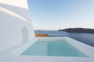 a white house with a swimming pool overlooking the ocean at The Architect's Cave House in Oia