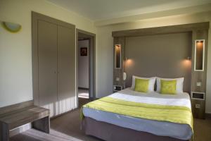 - une chambre avec un grand lit et des oreillers verts dans l'établissement Hotel Les Mésanges, à Saint-Martin-dʼUriage