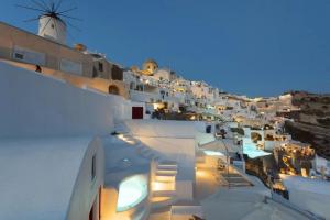 a view of a town at night with a windmill at The Architect's Cave House in Oia