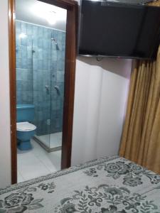 a bathroom with a shower and a television on a bed at Hotel Plata in Bogot&aacute;