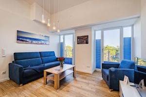 una sala de estar con sofás azules y una mesa. en FeWo Prora - Meerestraum, en Binz