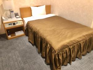 a hotel room with a bed and a night stand at Southern Cross Inn Matsumoto in Matsumoto