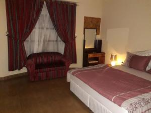 a bedroom with a bed and a chair and a window at Ahlam Musandam Villa in Khasab