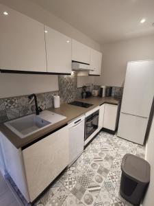 尼斯的住宿－2 pièces Vieux-Nice N，厨房配有白色橱柜和瓷砖地板。