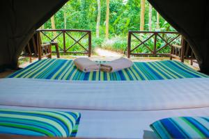 a bed in a tent with two towels on it at Kibale Forest Camp by NATURE LODGES LTD in Kyenjojo
