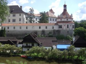 a building with a clock tower next to a river at Penzion U Tkadlen in Jindřichŭv Hradec