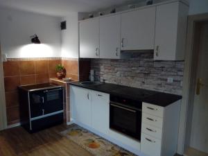una cocina con armarios blancos y un aparato negro en Haus Höber, en Archkogel