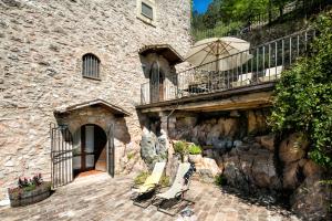 a stone building with a balcony and some lounge chairs at Residence Menotre in Rasiglia