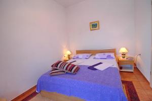 a bedroom with a bed with purple sheets and two lamps at Apartments Filipović in Sobra