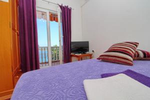 a bedroom with a purple bed and a balcony at Apartments Filipović in Sobra