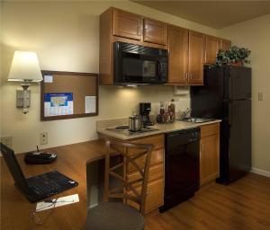 eine Küche mit Holzschränken und einem schwarzen Kühlschrank in der Unterkunft Candlewood Suites Avondale-New Orleans, an IHG Hotel in Avondale