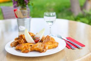 eine weiße Platte mit Hühnerflügeln und ein Glas Wein in der Unterkunft Gänschen klein in Ellscheid