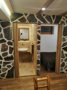 a bathroom with a sink and a rock wall at László apartman in Harghita-Băi