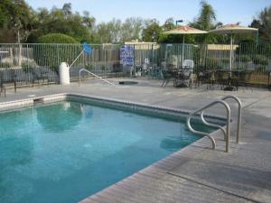 a swimming pool in a patio with tables and chairs at Edge Water Inn in Reedley